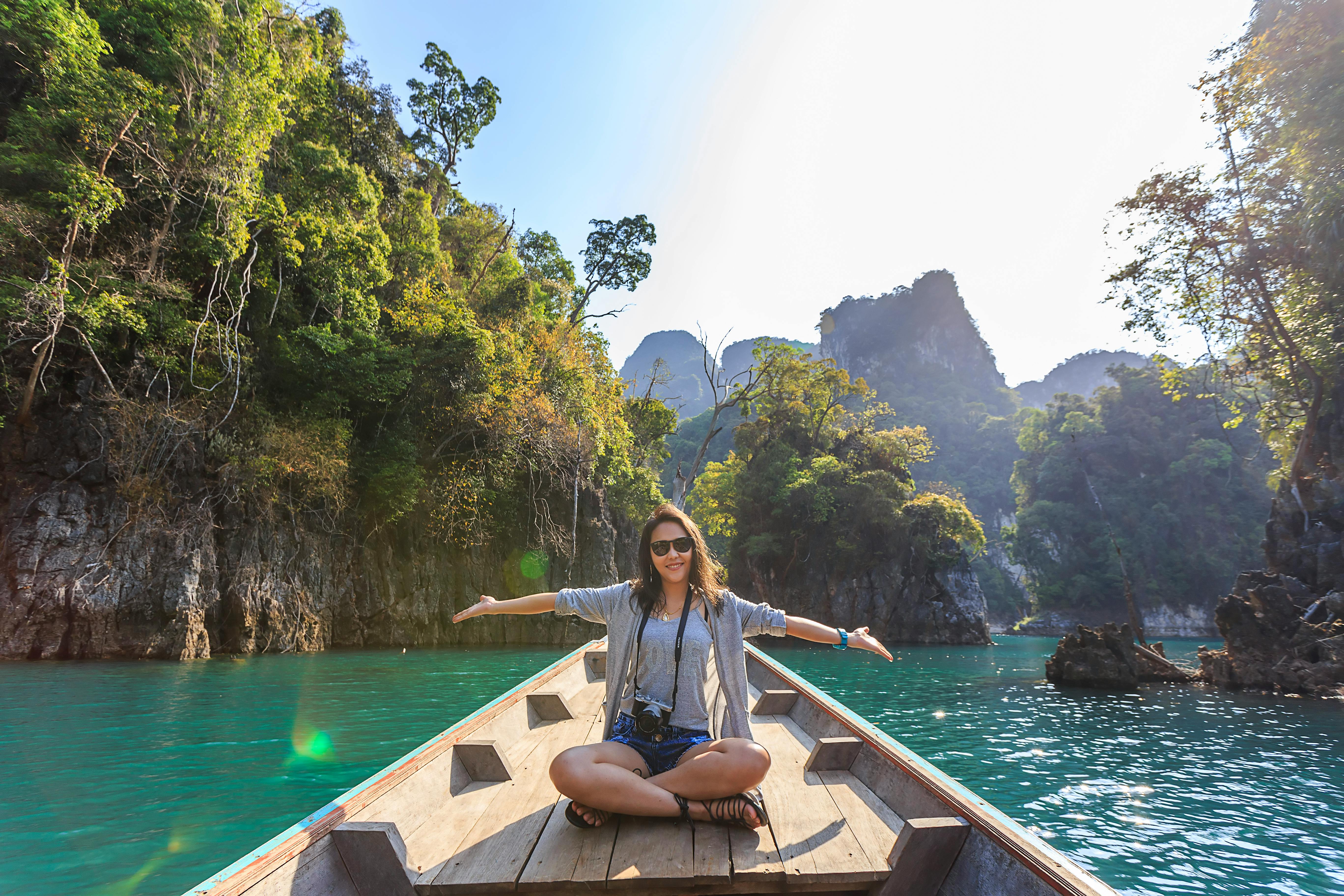 A serene, minimalist travel photo of a person's legs dangling over a calm, turquoise lake from a wooden pier, with misty mountains in the background, conveying a sense of peace and secure exploration.